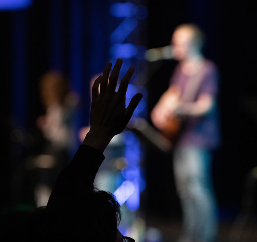 person raising hand in worship